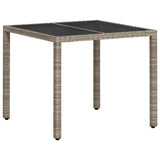 Garden table with light grey glass top and woven resin