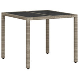 Garden table with light grey glass top and woven resin