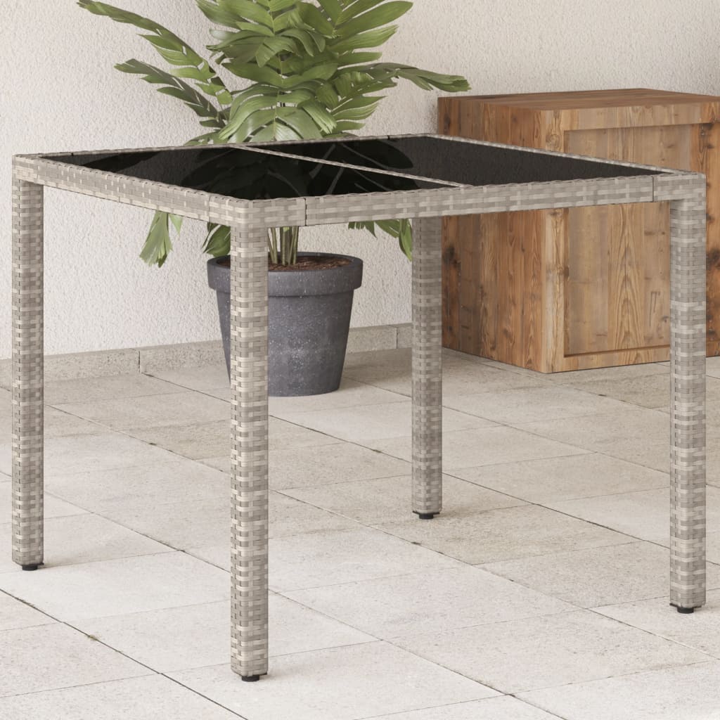 Garden table with light grey glass top and woven resin