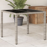 Garden table with light grey glass top and woven resin